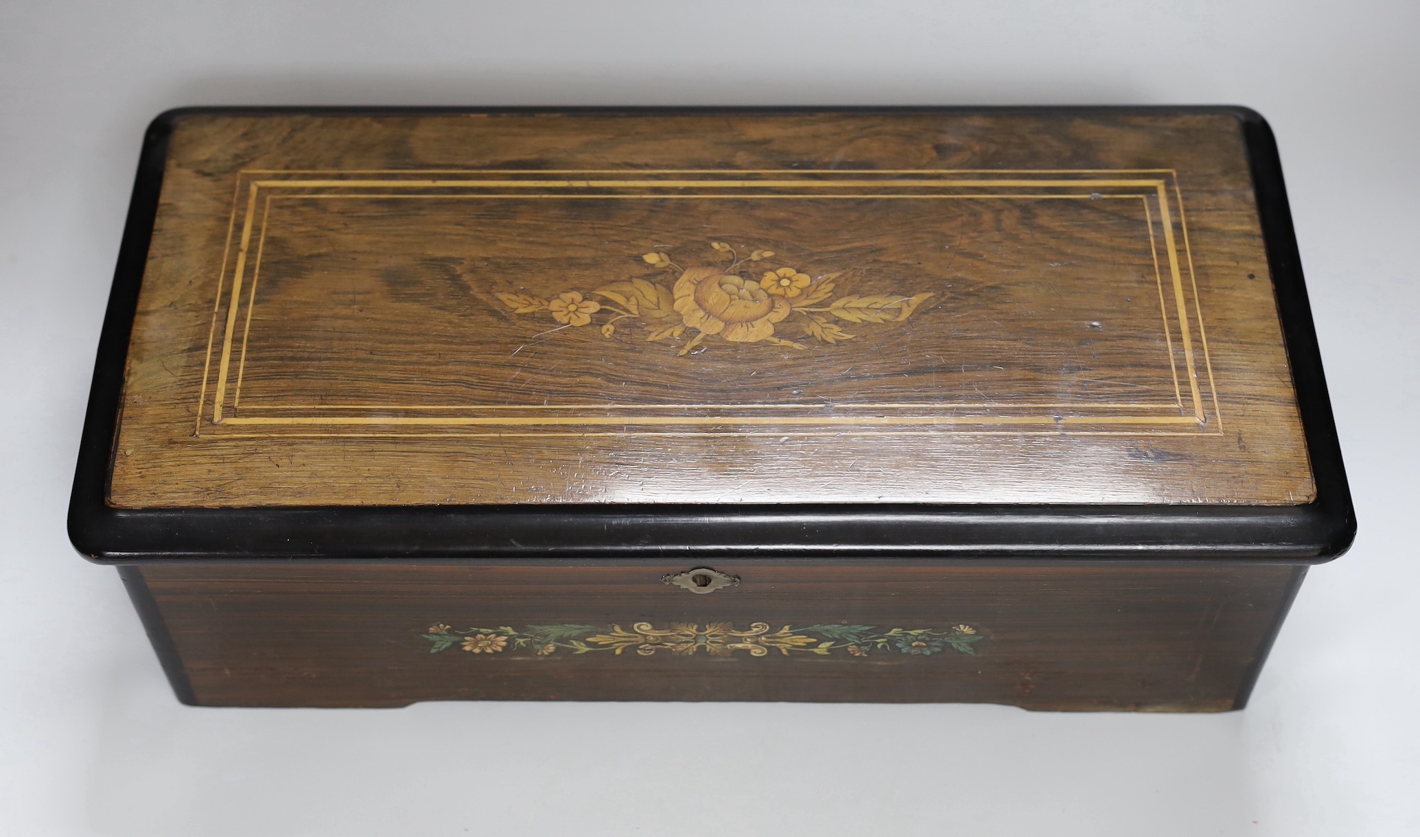 A late 19th century Swiss rosewood and marquetry cased cylinder music box, playing six airs, lacking tune sheet, 43cms wide x 14cms high